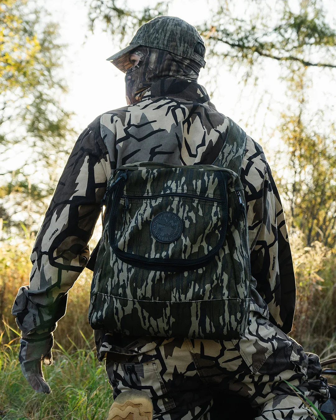 Man in hunting clothes wearing a Duluth Pack Blind Bag with a forest in the background