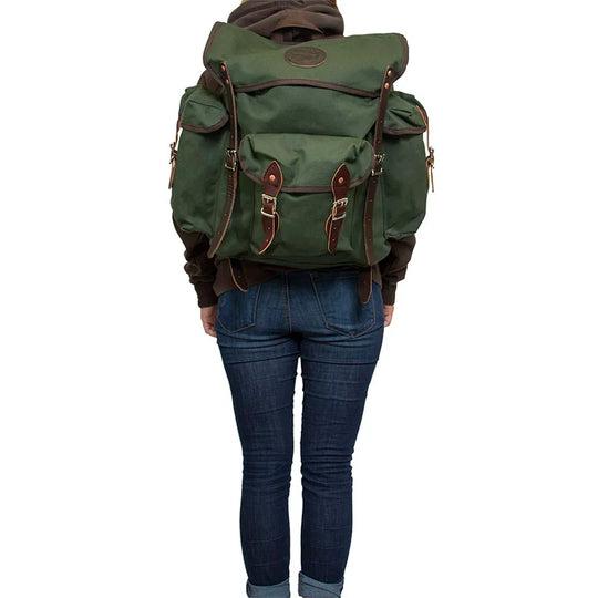 Wanderer backpack in Olive Drab with hand-cut leather reinforcements, durable canvas for rugged outdoor use, worn by a person dressed for adventure.