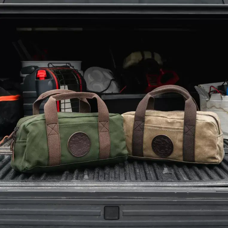 Two Utility Bags, One In Olive Drab Green And The Other In Waxed Khaki In The Bed Of A Truck Full Of Ice Fishing Gear 