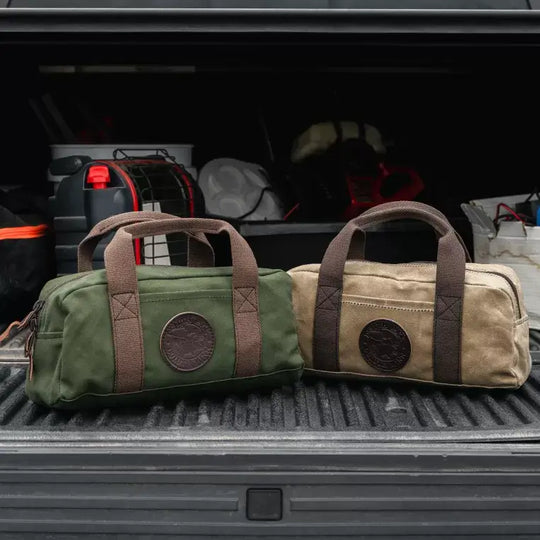 Two Utility Bags, One In Olive Drab Green And The Other In Waxed Khaki In The Bed Of A Truck Full Of Ice Fishing Gear 