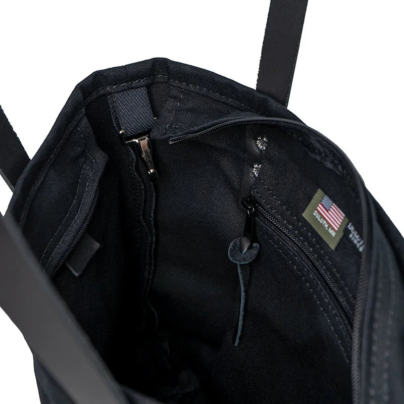 Superior Series Canvas Lakewalk Tote in black canvas with leather accents, showing durable handmade interior pockets and rugged craftsmanship by Duluth Pack for outdoor use.