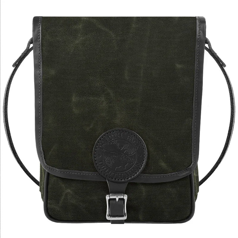 Haversack in rugged waxed olive canvas with premium leather trim and antique brass hardware, designed by Duluth Pack for durable outdoor use.