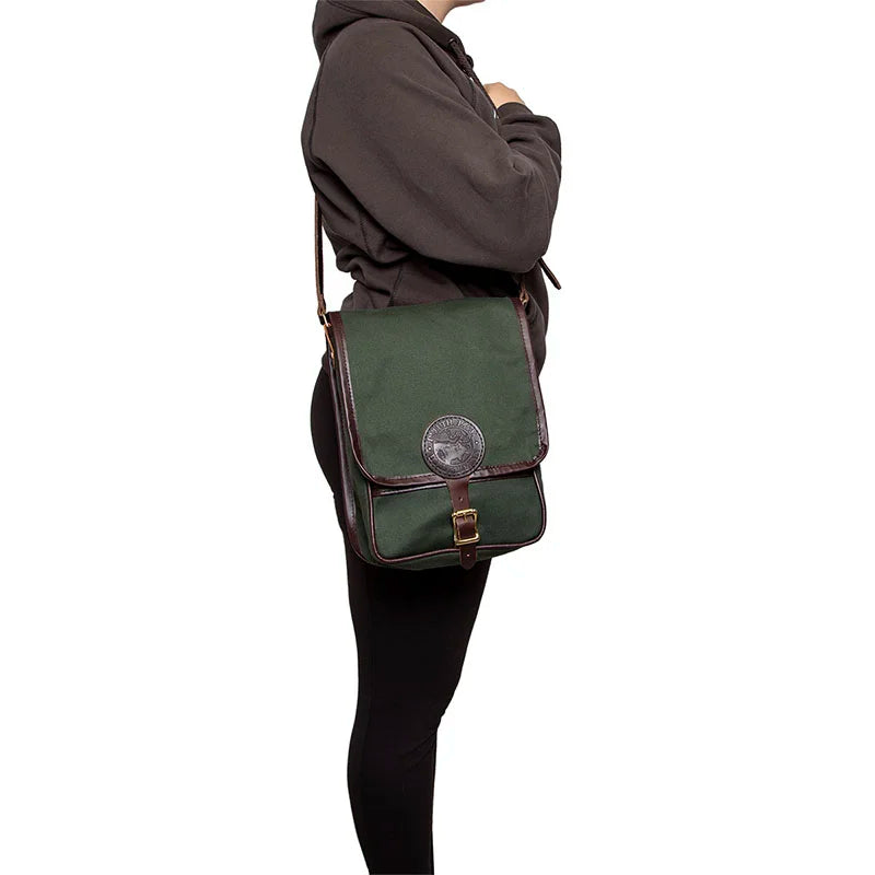 Haversack in rugged 15-ounce green canvas with premium leather accents, worn over the shoulder, showcasing durable outdoor craftsmanship by Duluth Pack.
