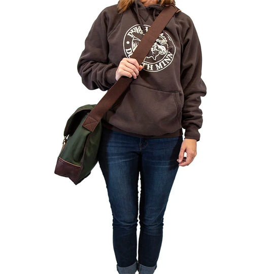 Deluxe Book Bag in Olive Drab with handcrafted leather trim and cotton web strap, worn by person showcasing rugged outdoor gear for durable everyday use.
