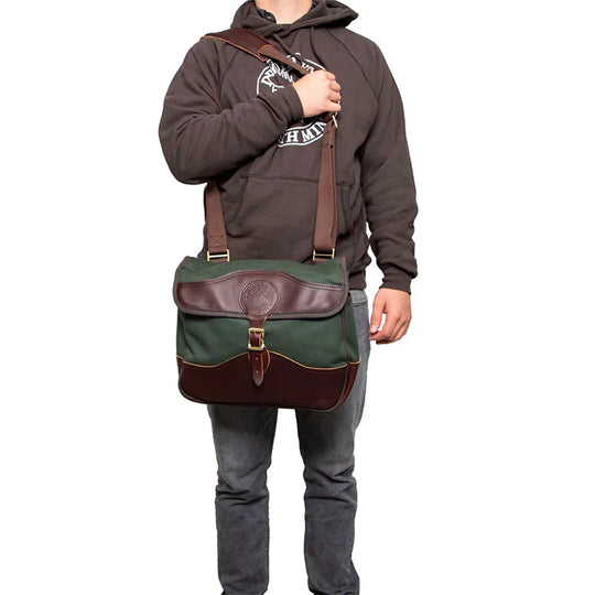 Field Satchel in rugged 15-ounce canvas with thick leather accents and adjustable strap, worn by a person modeling durable outdoor gear by Duluth Pack.