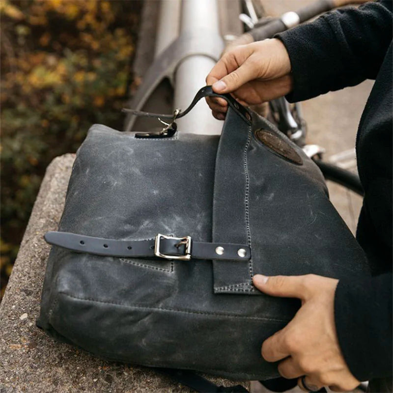 Ranger Pack in waxed grey canvas with premium leather straps, shown being opened outdoors, highlighting its rugged handmade design for durable everyday use.
