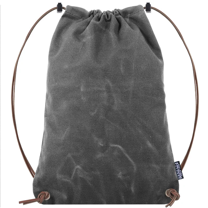 Drawstring Backpack in rugged grey waxed canvas with premium adjustable leather drawstrings, crafted by Duluth Pack for durable outdoor use.