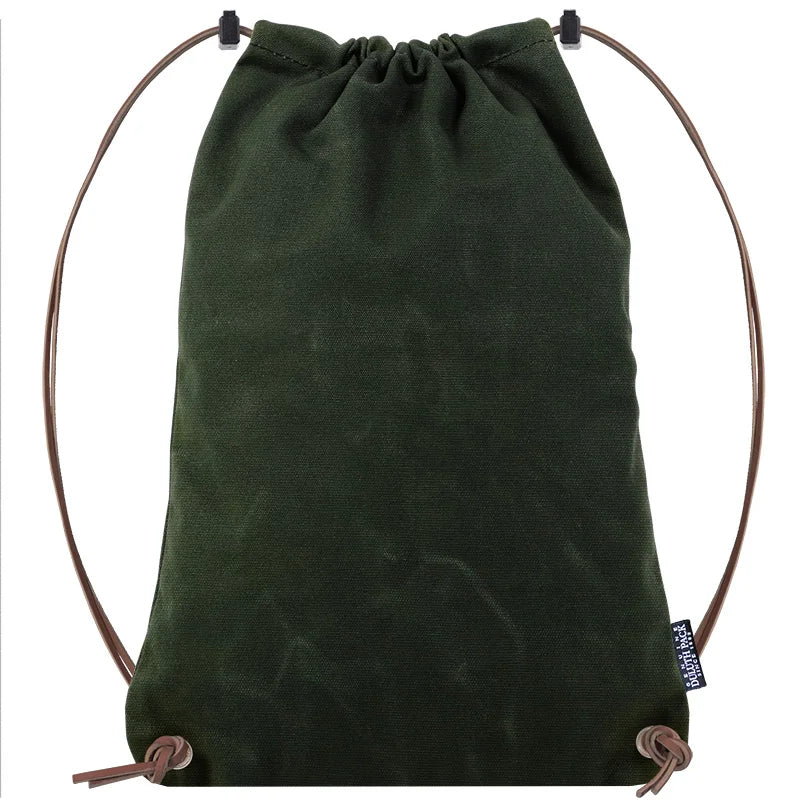 Drawstring Backpack in dark green canvas with premium leather adjustable straps by Duluth Pack, designed for rugged outdoor use and long-lasting durability.