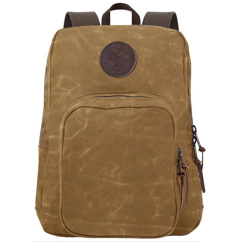 Large Standard Backpack in waxed khaki canvas with antique brass hardware, featuring durable construction and rugged outdoor style by Duluth Pack.