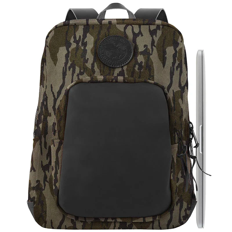 Deluxe Laptop Backpack in Mossy Oak Bottomland Camo with rugged canvas and leather front pocket, shown with a laptop to highlight protective outdoor gear quality.
