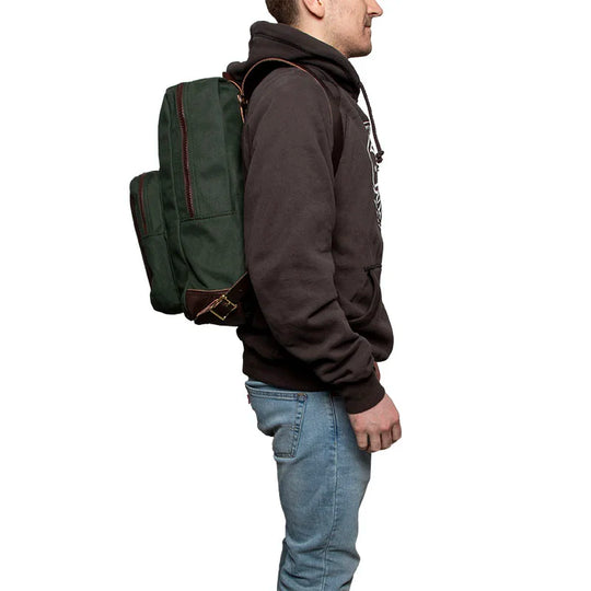 Deluxe Laptop Backpack in olive drab canvas with leather accents, worn by a man dressed for outdoor use, showcasing rugged and durable craftsmanship.