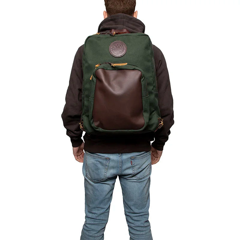 Deluxe Laptop Backpack in Olive Drab with leather pocket, worn by a person against a white background, showcasing rugged outdoor craftsmanship by Duluth Pack.