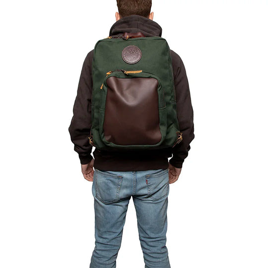 Deluxe Laptop Backpack in Olive Drab with leather pocket, worn by a person against a white background, showcasing rugged outdoor craftsmanship by Duluth Pack.