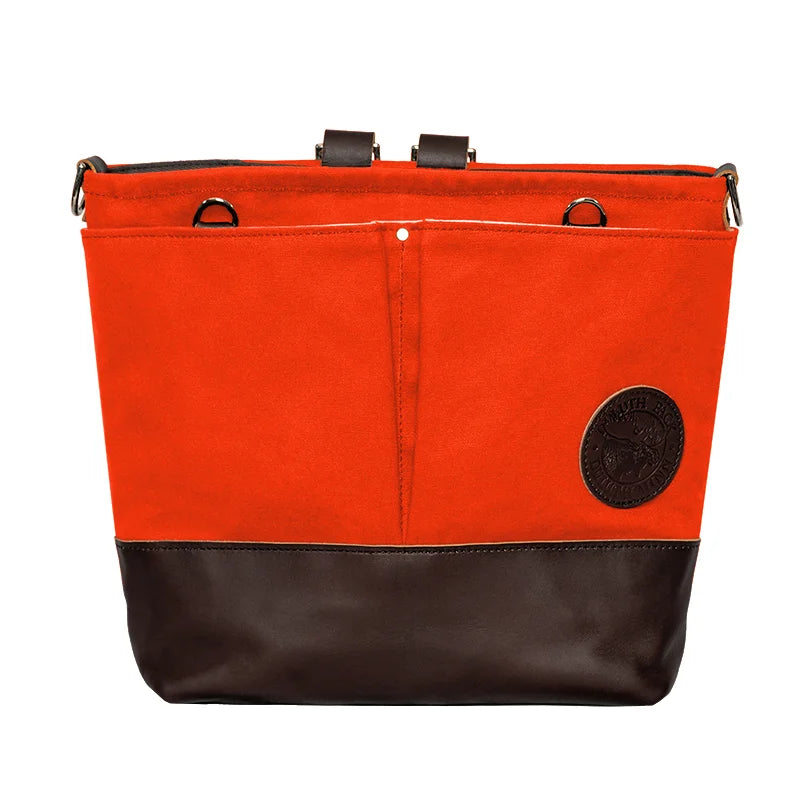 Convertible Jet-Setter Tote in orange canvas with dark leather bottom, featuring multiple attachment points and front pockets, crafted by Duluth Pack for rugged outdoor use.