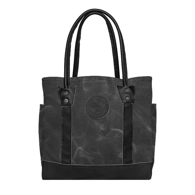 Highlander Tote in waxed grey canvas and leather, featuring durable craftsmanship and interior pockets, perfect for everyday outdoor use by Duluth Pack.