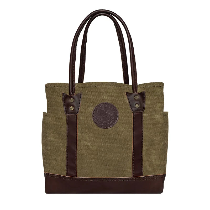 Highlander Tote in waxed khaki with dark leather accents, featuring durable canvas and leather construction, ideal for rugged outdoor use by Duluth Pack.