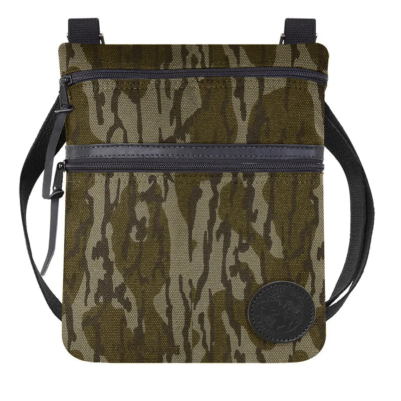 Traverse Crossbody Bag in Mossy Oak Bottomland Camo featuring durable canvas construction and dual zippered compartments, ideal for rugged outdoor use.