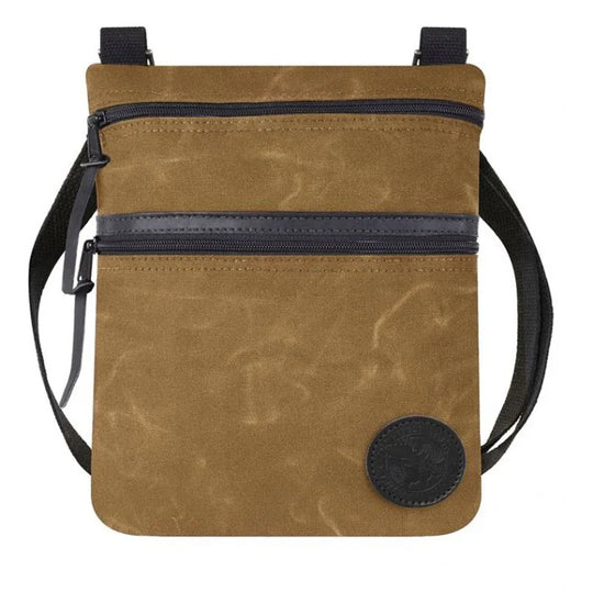 Traverse Crossbody Bag in waxed khaki canvas with black zippers and adjustable strap, designed by Duluth Pack for durable outdoor use and everyday carry.