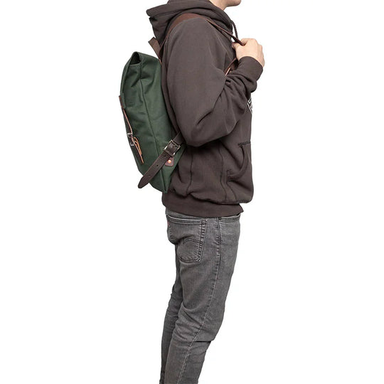 Scout Pack in Olive Drab canvas with leather straps worn by a person in casual outdoor clothing, showcasing rugged handmade quality for outdoor adventures.