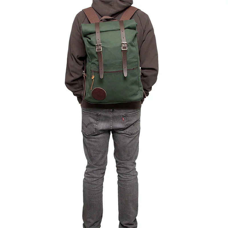 Roll-Top Scout Pack in green canvas with leather straps worn by a person, showcasing durable craftsmanship for outdoor gear and versatile use.