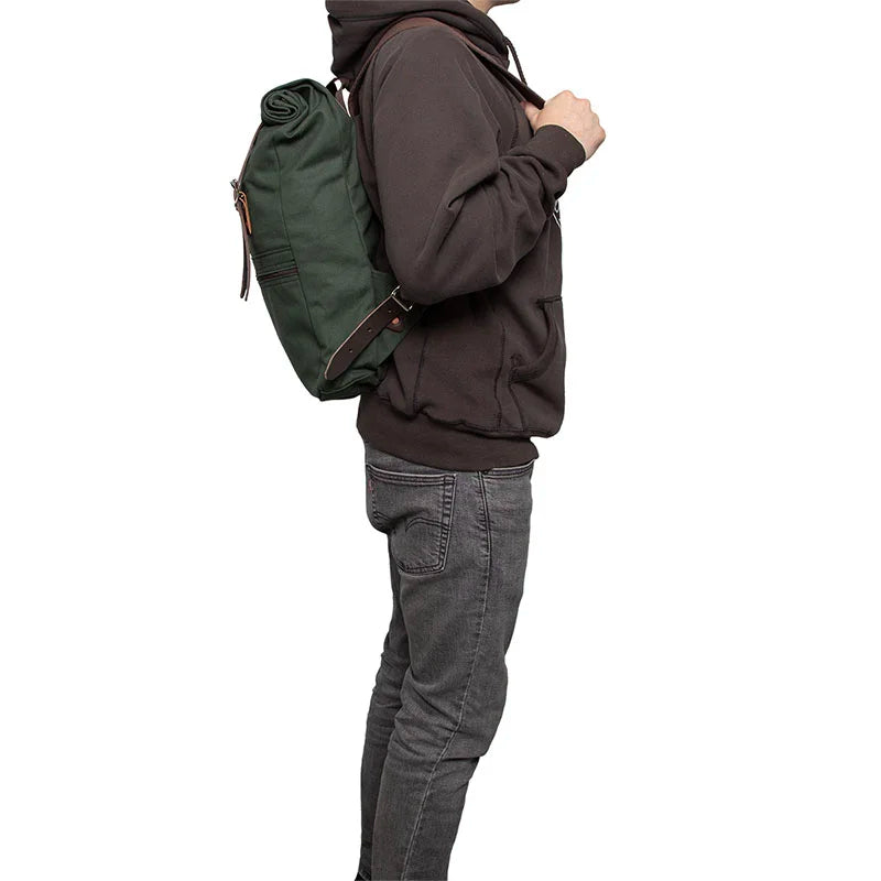 Roll-Top Scout Pack in durable green canvas with leather straps worn by a person in casual outdoor attire, ideal for versatile hiking and everyday use.