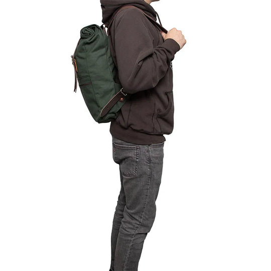 Roll-Top Scout Pack in durable green canvas with leather straps worn by a person in casual outdoor attire, ideal for versatile hiking and everyday use.