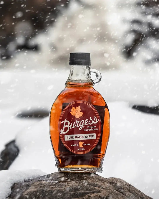 Bottle of Burgess Pure Maple Syrup in an 8 Oz size on a snowy background
