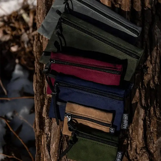 A Size Comparison Of All 3 Sizes Of The Gear Stash Bag (2 of each size in various colors) resting on a log.