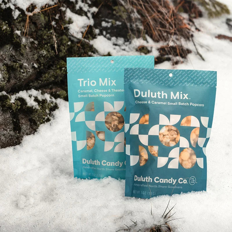 Duluth Candy Co. Popcorn Mix in trio and duluth mix with a snowy background