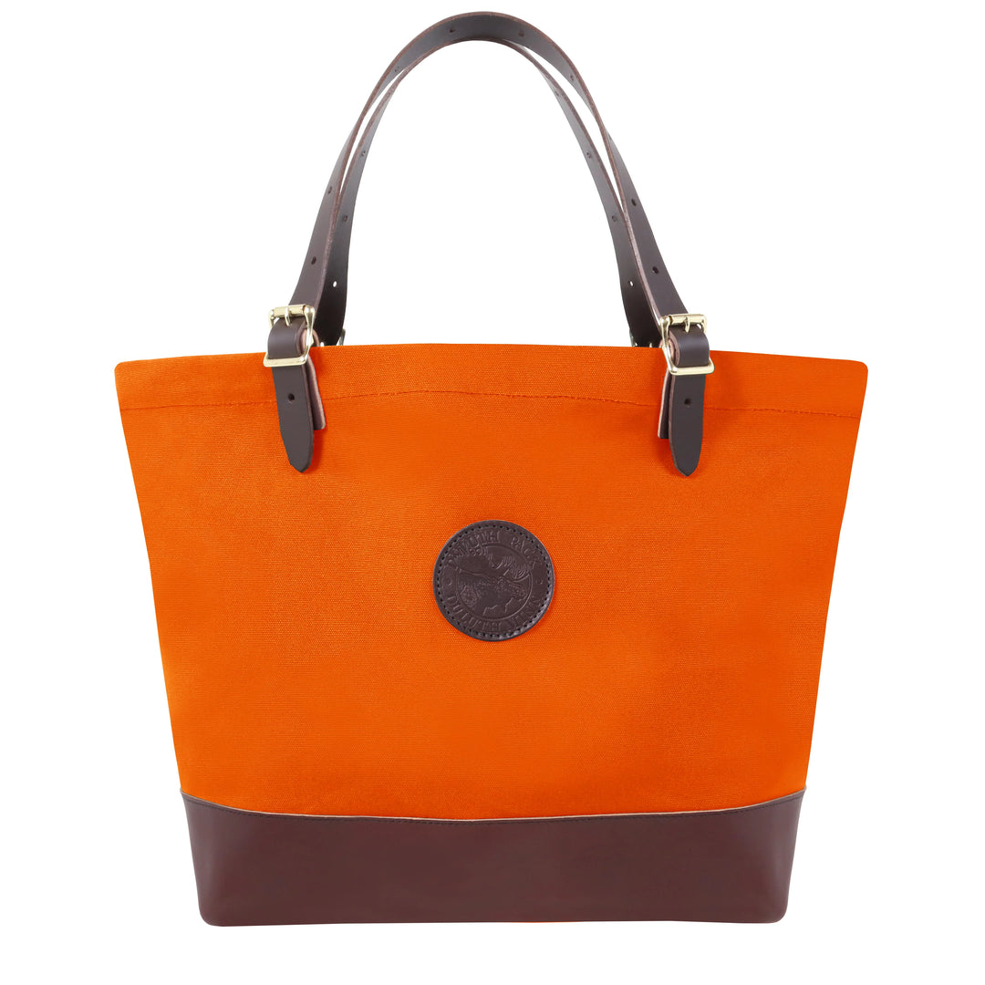 Deluxe Market Tote in hunter’s orange with dark leather handles and base, crafted by Duluth Pack for rugged outdoor use and durable everyday carrying.
