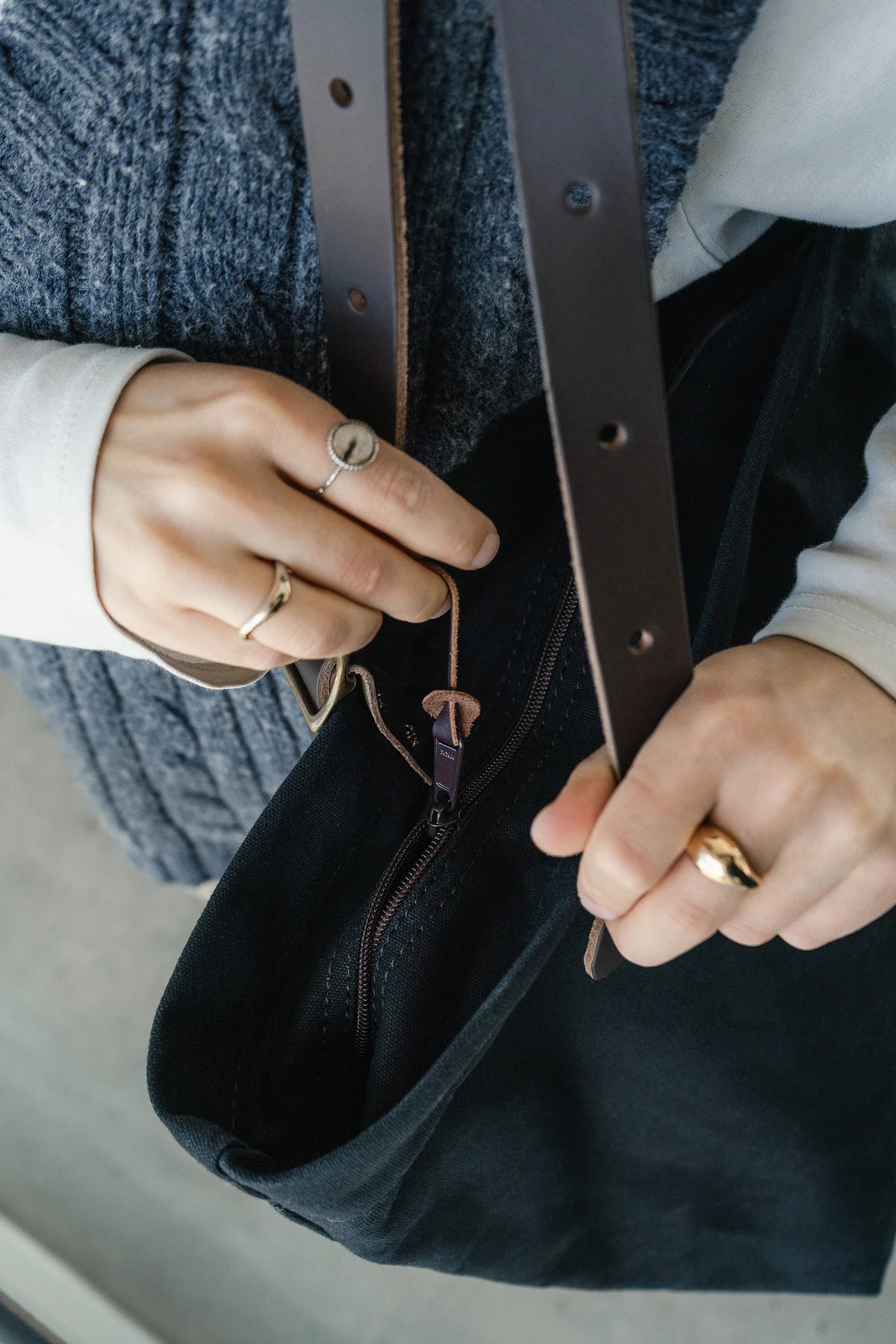 Woman unzipping the new Duluth Pack Zippered Market Tote with her blue sweater in the background