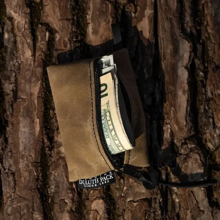 Small Gear Stash Bag In Waxed Khaki With Money Sticking Out On A Log Background