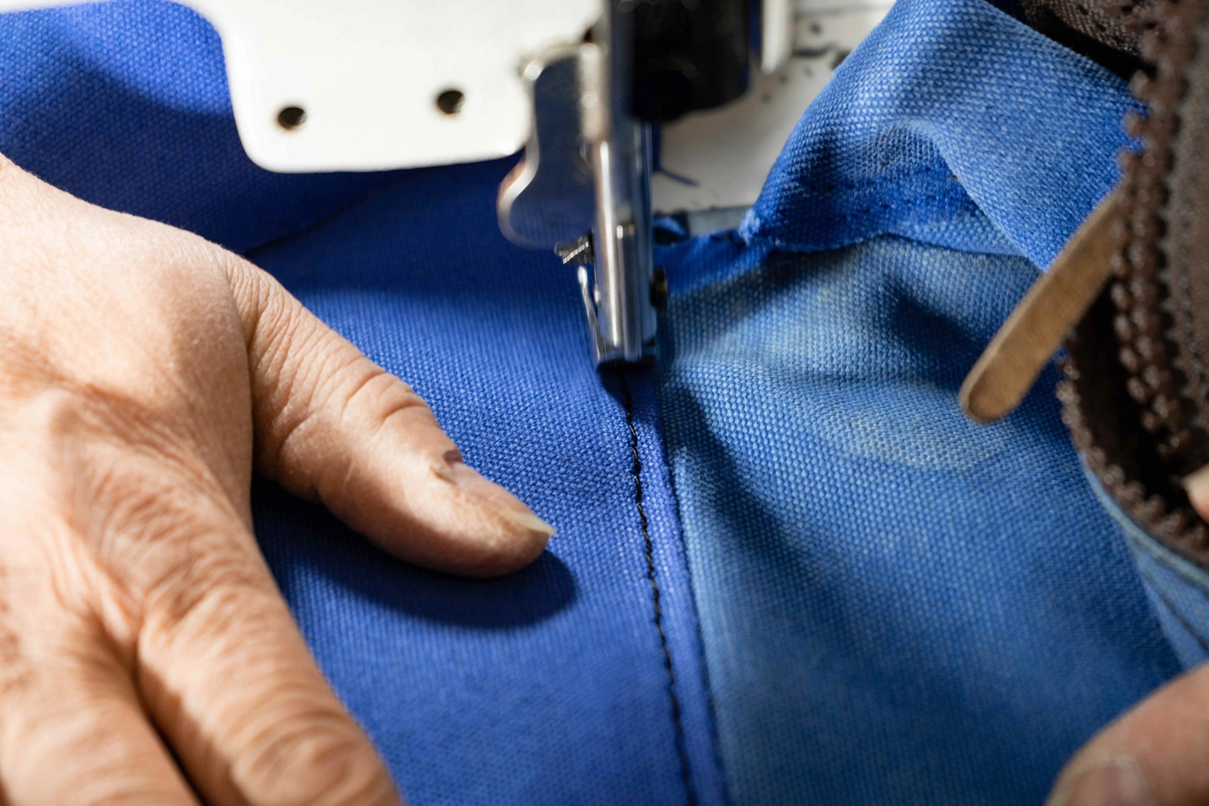person repairing a broken duluth pack with a sewing machine