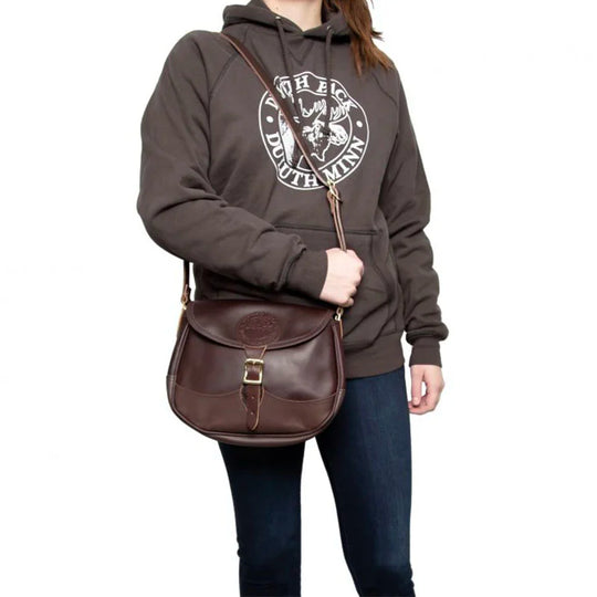 Medium Leather Shell Purse in rich brown premium leather, worn crossbody by a person in casual outdoor apparel, showcasing durable craftsmanship and tradition.