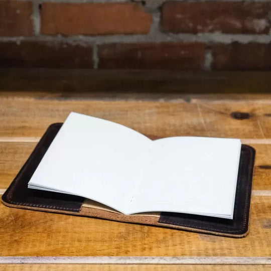 Heritage Leather Field Journal on a table with a brick background