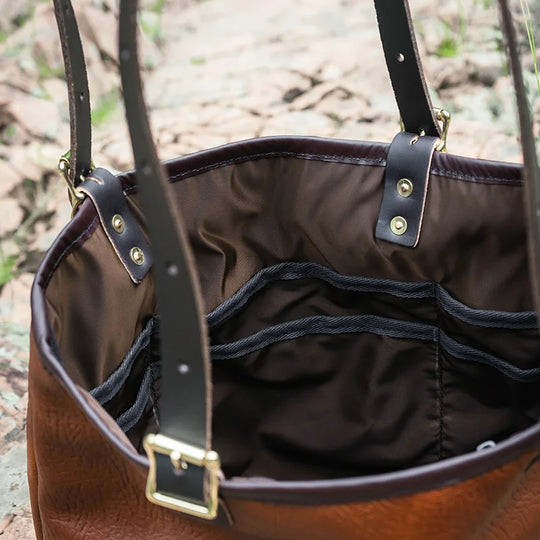 Duluth Pack Bison Leather Travel Tote in brown trim with forest background