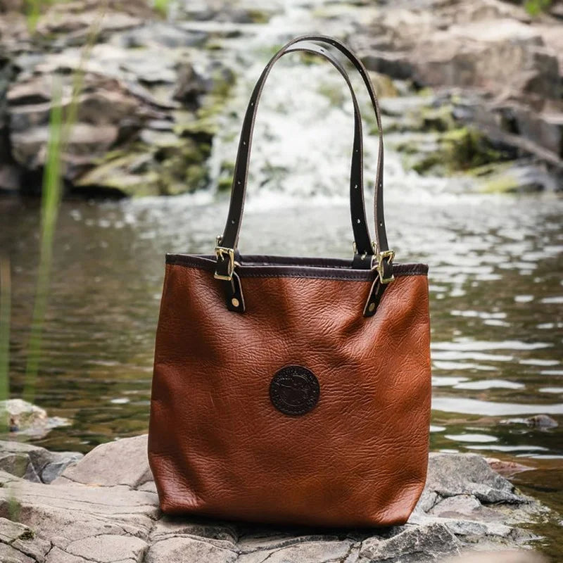 Duluth Pack Bison Leather Travel Tote in brown trim with waterfall in the background