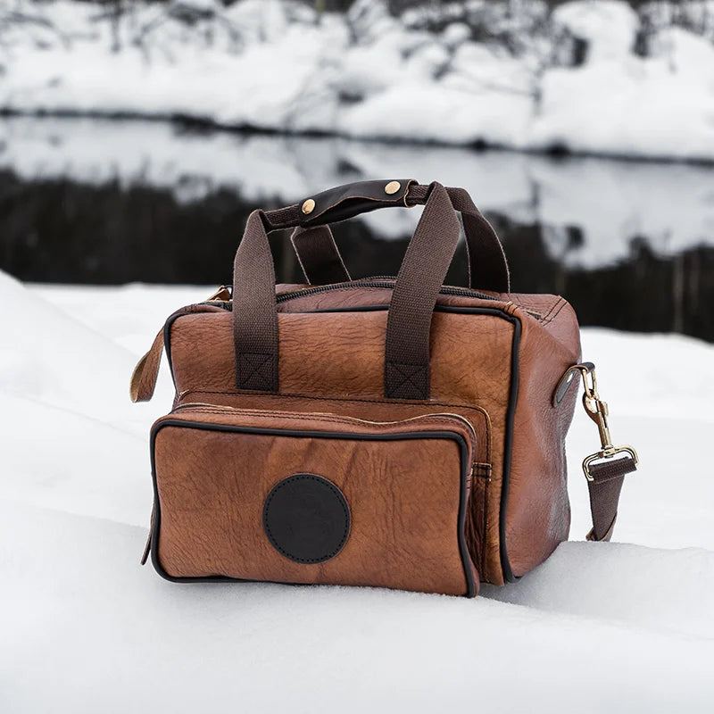 Duluth Pack Bison Leather Range Bag with black trim with snowy background