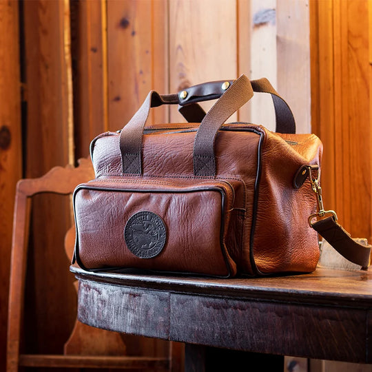 Duluth Pack Bison Leather Range Bag with black trim with wood background
