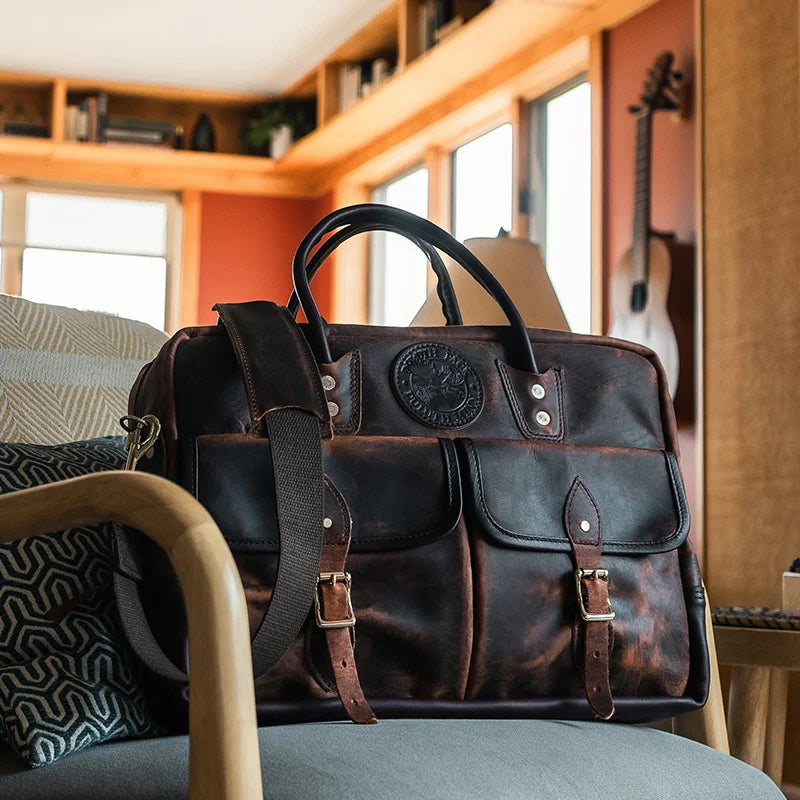 Heritage Leather Freelance Briefcase sitting on a chair with a living room in the background