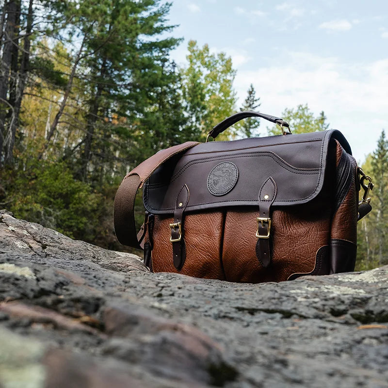 Duluth Pack Bison Leather Entrepreneur Briefcase with brown trim with rocky and forest background