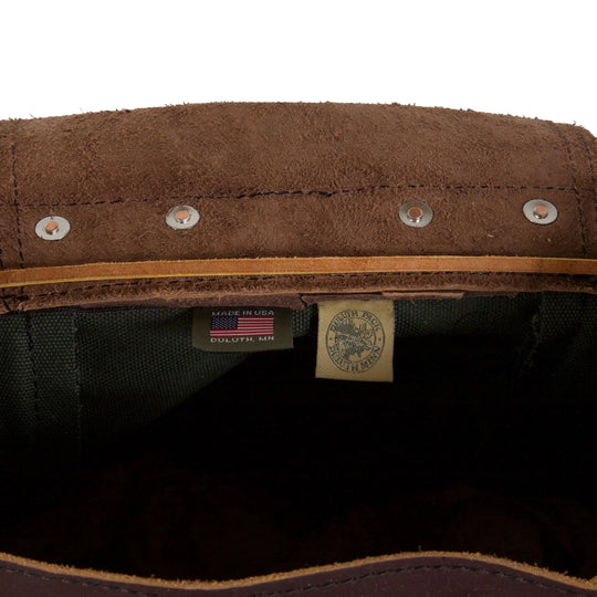 Rucksack Backpack in rugged waxed canvas with leather trim showing reinforced rivets and maker labels inside, highlighting durable craftsmanship by Duluth Pack.