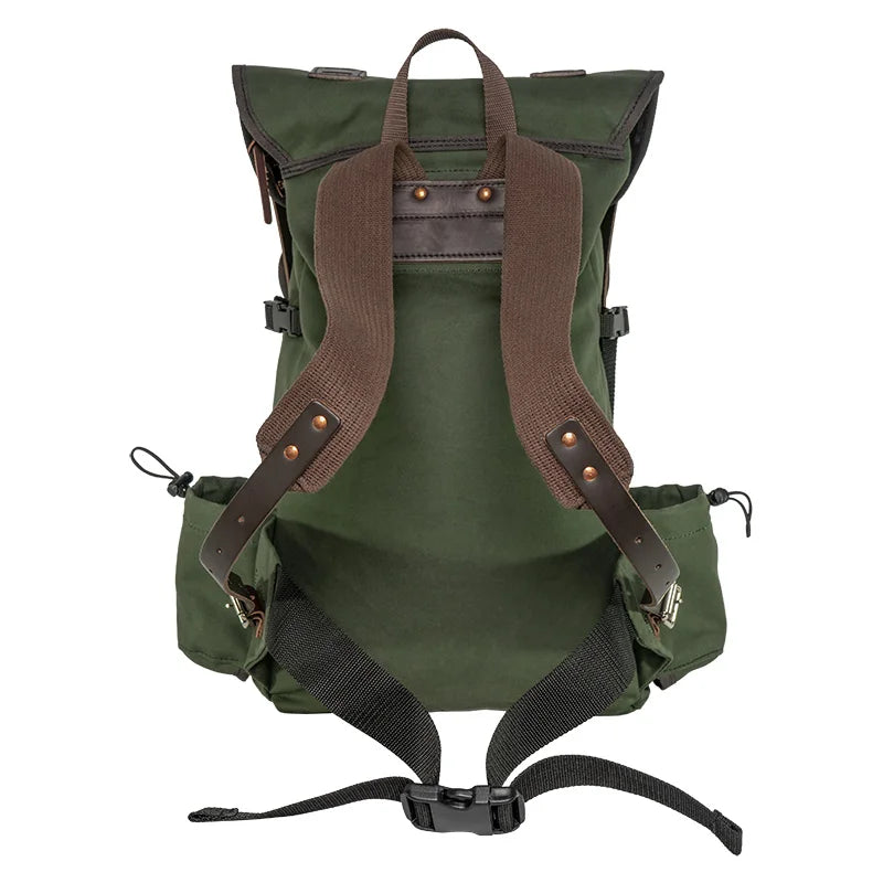 Outlander Pack in durable green canvas with leather accents by Duluth Pack, designed for rugged outdoor use on narrow trails and dense wilderness.