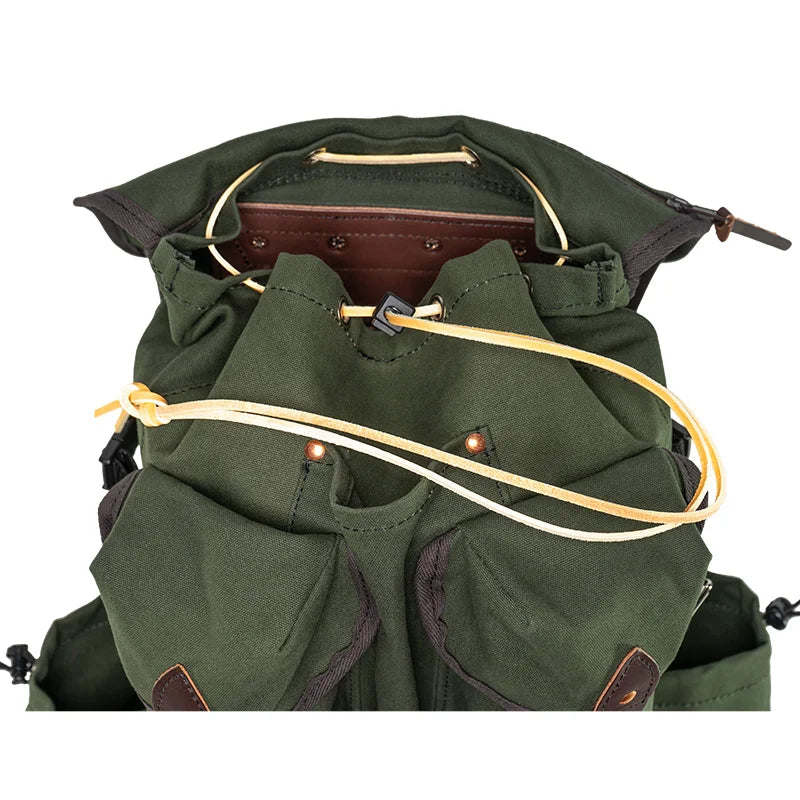Outlander Pack in dark green canvas with leather accents and drawcord closure, designed for rugged outdoor use and tight trail navigation.