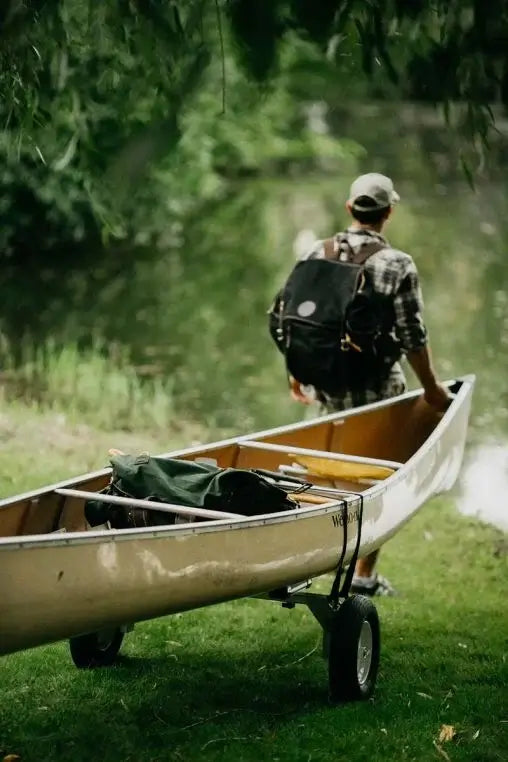 Spring Creek Canoe/Kayak Portage Cart attached to a canoe being pulled by a man headed towards a lake