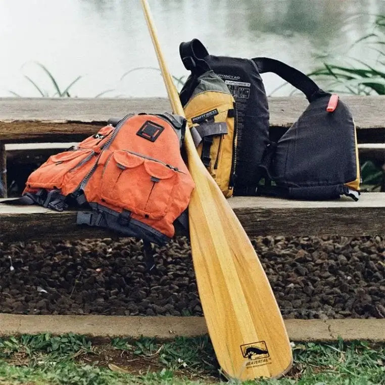 Bending Branches Beavertail Paddle Resting on a fence on the shore with 2 lifejackets