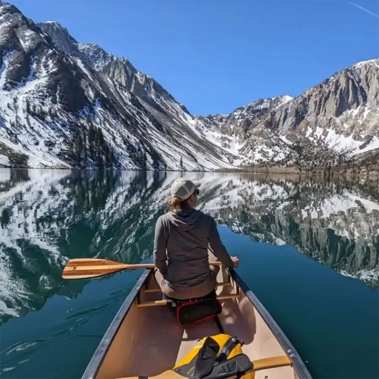 Bending Branches Explorer Plus Paddle Being used by a woman in a canoe in a lake with a mountain backdrop