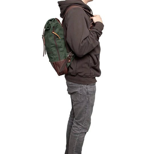 Deluxe Roll-Top Scout Pack in Olive Drab canvas and leather, worn by person outdoors, showcasing durable handmade craftsmanship by Duluth Pack for rugged use.