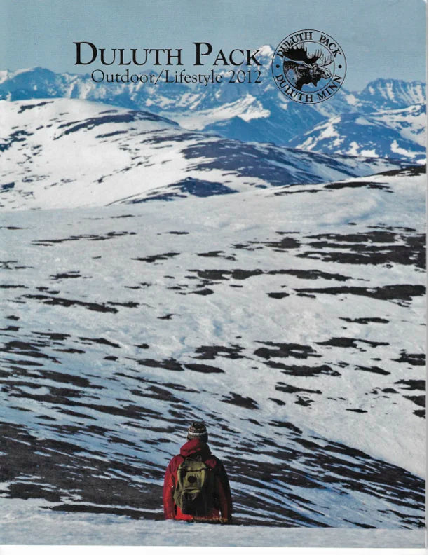 Duluth Pack canvas backpack in snowy mountain wilderness setting, capturing rugged outdoor lifestyle and heritage craftsmanship from 2012 collection.