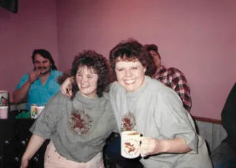 Photo: Image of two women laughing and hugging wearing Duluth Pack t-shirts. 